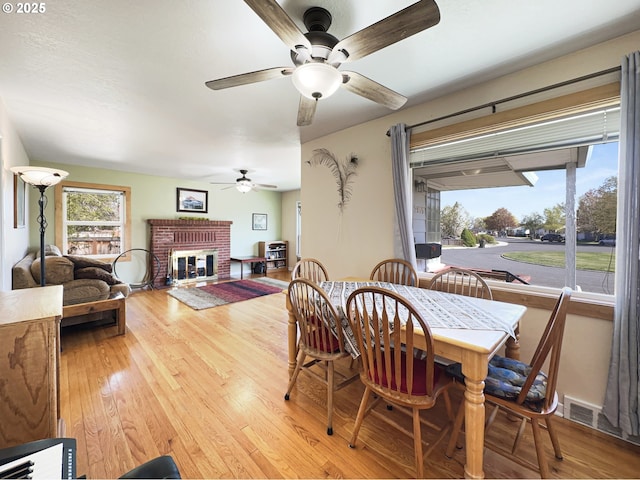 dining room with a ceiling fan, hardwood / wood-style floors, a fireplace, and visible vents