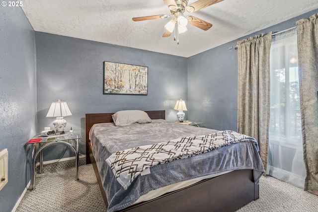 carpeted bedroom featuring ceiling fan and a textured ceiling