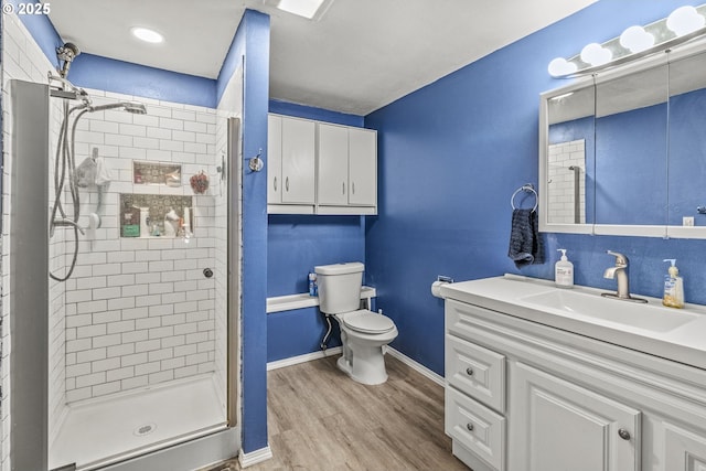 bathroom with toilet, hardwood / wood-style floors, walk in shower, and vanity