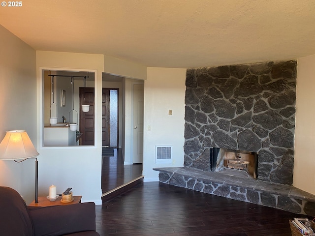 living room with dark wood-type flooring and a stone fireplace