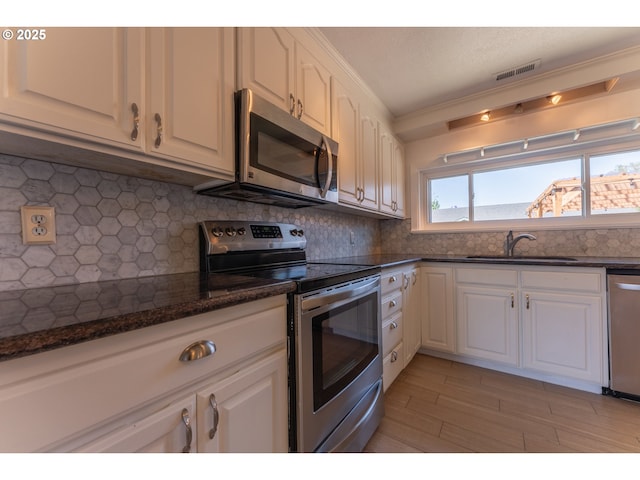 kitchen with a sink, white cabinets, stainless steel appliances, and visible vents