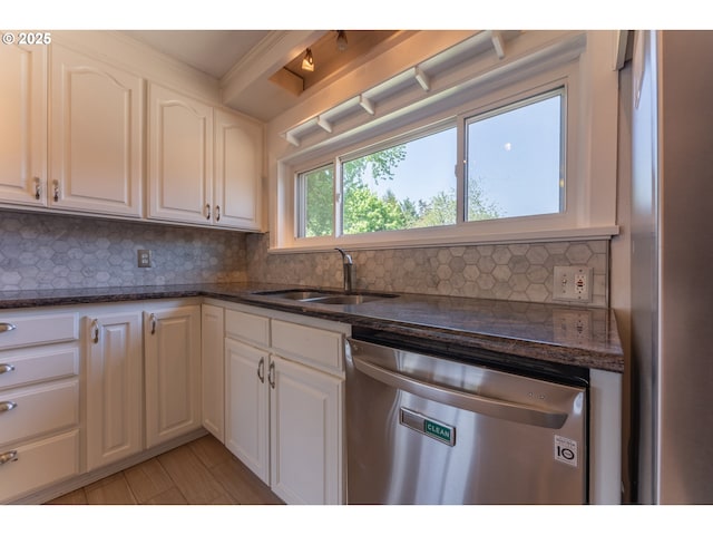 kitchen with a sink, white cabinets, stainless steel dishwasher, and tasteful backsplash