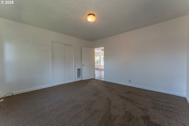 spare room with baseboards, carpet flooring, a textured ceiling, and visible vents