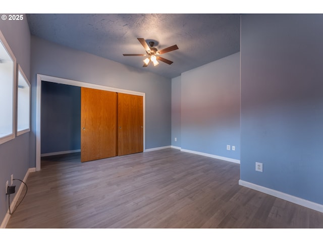 unfurnished bedroom featuring baseboards, wood finished floors, and a closet