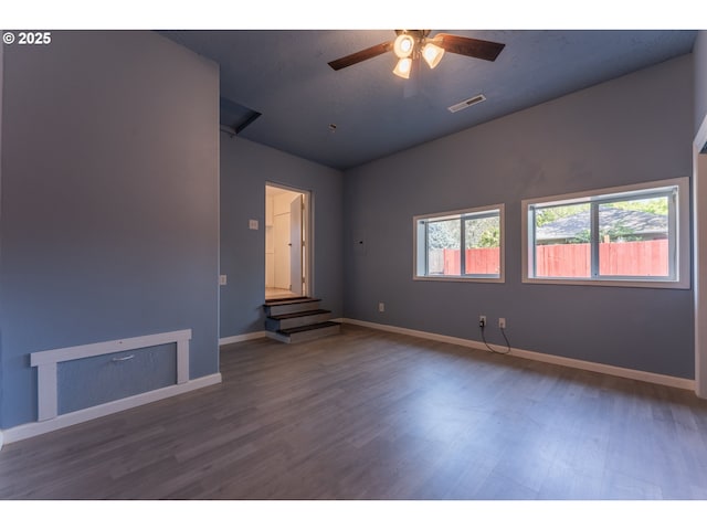 empty room with a ceiling fan, baseboards, wood finished floors, vaulted ceiling, and visible vents