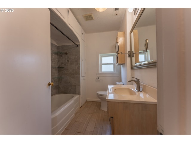 bathroom with shower / bath combination, visible vents, wood finished floors, vanity, and toilet