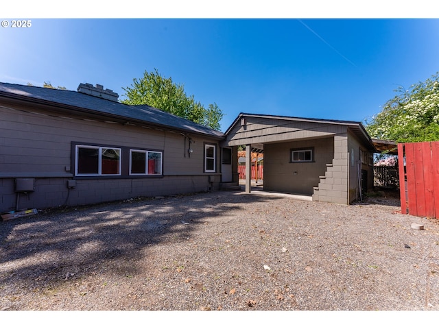 view of front of home featuring fence, concrete block siding, and an attached carport