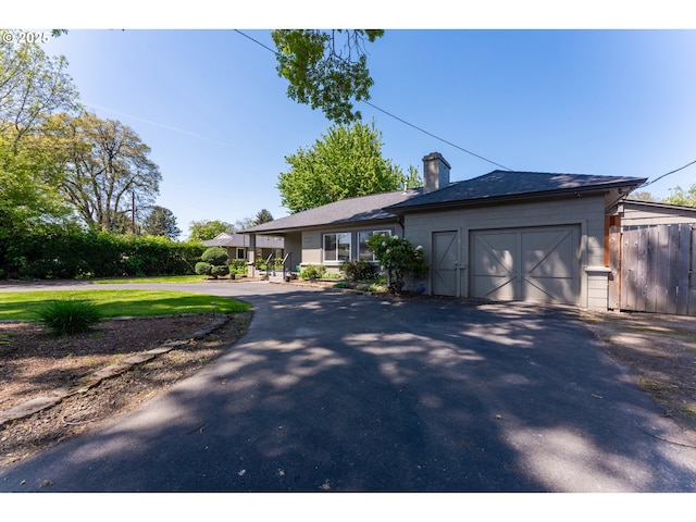 ranch-style home featuring fence, an attached garage, driveway, and a chimney