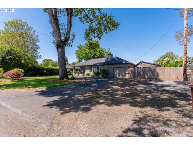 ranch-style home featuring an attached garage, fence, and driveway
