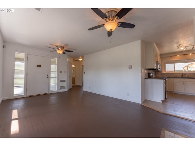 unfurnished living room with a sink, baseboards, ceiling fan, and wood finished floors