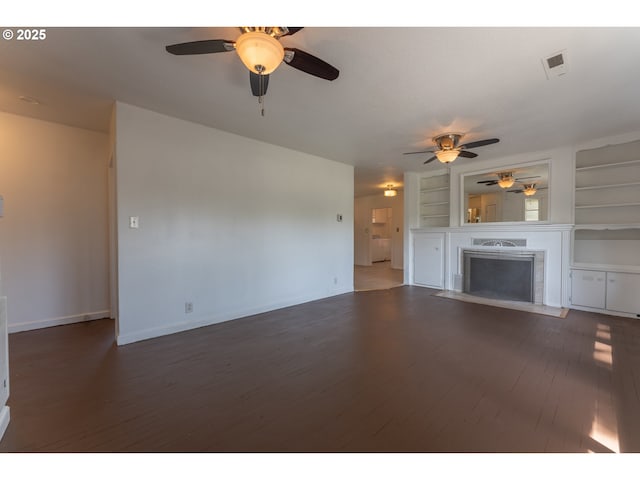unfurnished living room with built in features, wood finished floors, a fireplace, baseboards, and ceiling fan