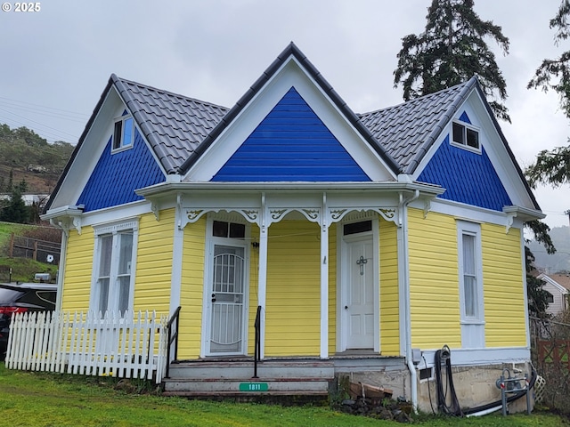 view of front of house featuring metal roof, a tile roof, and a porch