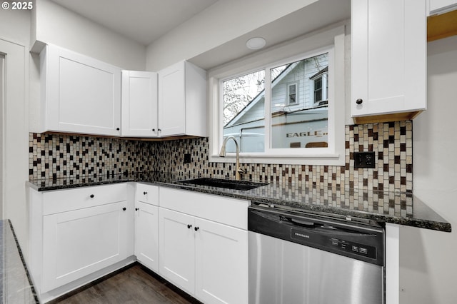 kitchen with white cabinets, dark stone counters, dishwasher, backsplash, and a sink