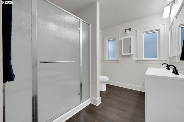 full bathroom with a stall shower, baseboards, toilet, wood finished floors, and vanity