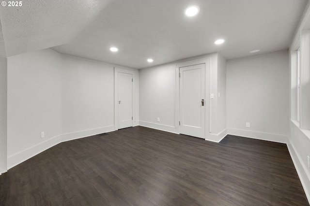 basement featuring visible vents, baseboards, dark wood finished floors, a textured ceiling, and recessed lighting