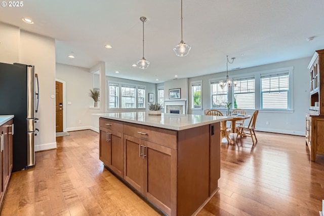 kitchen with freestanding refrigerator, baseboards, a center island, light wood-style floors, and recessed lighting