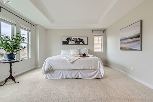 bedroom featuring a raised ceiling, carpet flooring, and baseboards