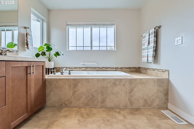 full bathroom featuring a garden tub, vanity, and tile patterned flooring