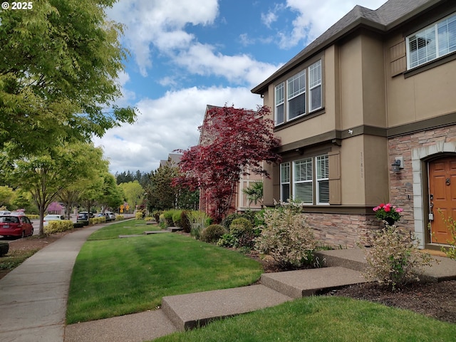 view of side of property with stone siding, stucco siding, and a lawn