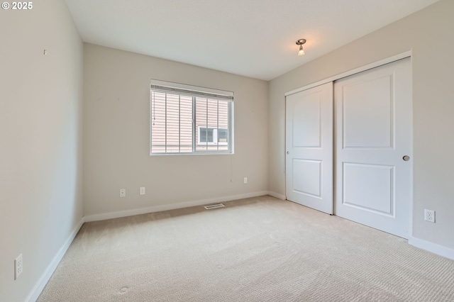 unfurnished bedroom featuring light carpet, baseboards, and a closet