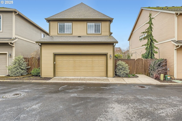 view of front of house featuring roof with shingles, fence, and an attached garage