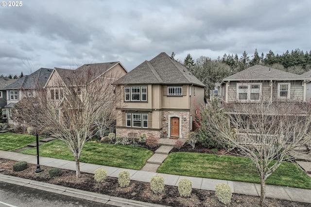 view of front of house featuring stone siding, a shingled roof, and a front lawn