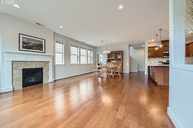 living room with a chandelier, wood finished floors, baseboards, recessed lighting, and a tile fireplace