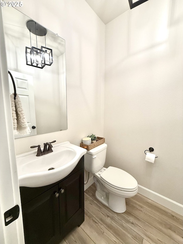 bathroom with wood-type flooring, toilet, and vanity