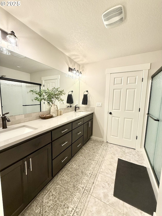 bathroom featuring vanity, an enclosed shower, and a textured ceiling