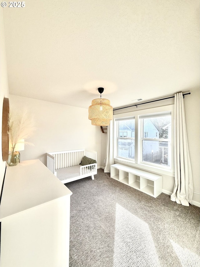 carpeted bedroom featuring a textured ceiling and a crib