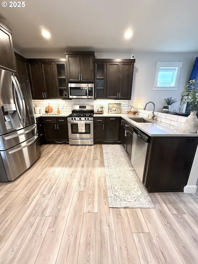 kitchen featuring tasteful backsplash, sink, light hardwood / wood-style floors, kitchen peninsula, and stainless steel appliances