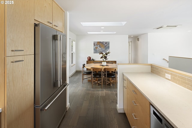 8630 SW 61st Ave, Portland, OR 97219 - kitchen featuring stainless steel appliances, light brown cabinetry, a skylight, dark wood-type flooring, and decorative backsplash