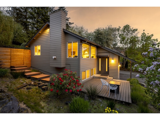 rear view of property featuring a deck, fence, and a chimney