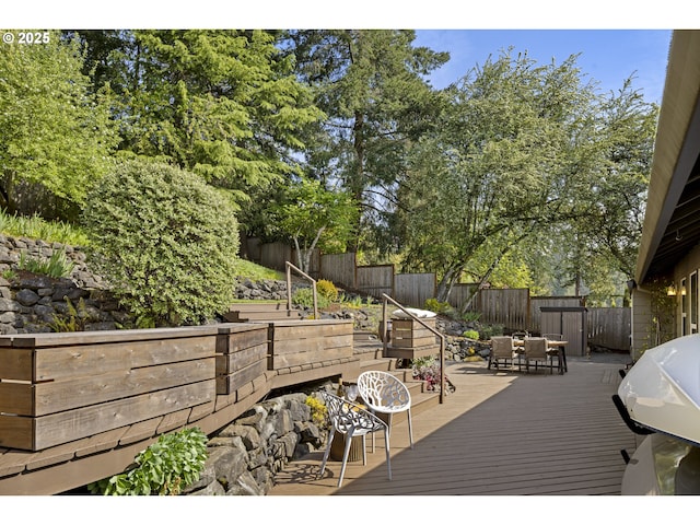 deck with outdoor dining area, a fenced backyard, and grilling area