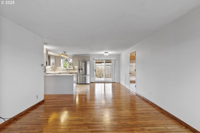 unfurnished living room featuring a textured ceiling and light wood finished floors