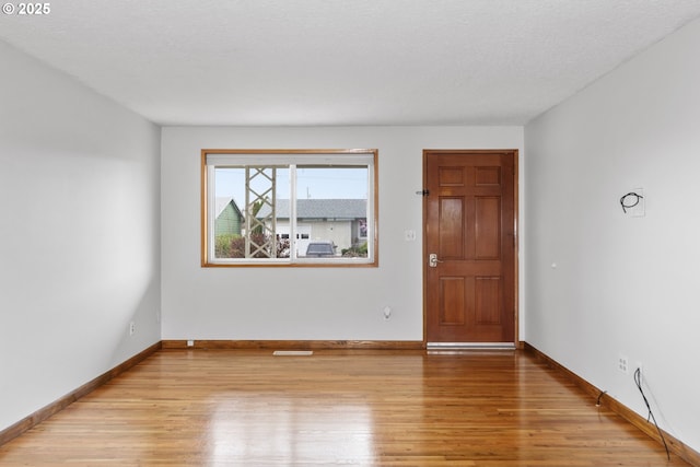 spare room featuring light wood-type flooring and baseboards