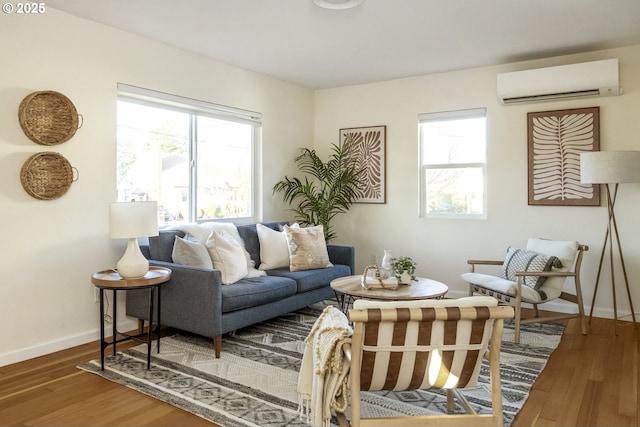 living room featuring an AC wall unit, wood finished floors, and baseboards