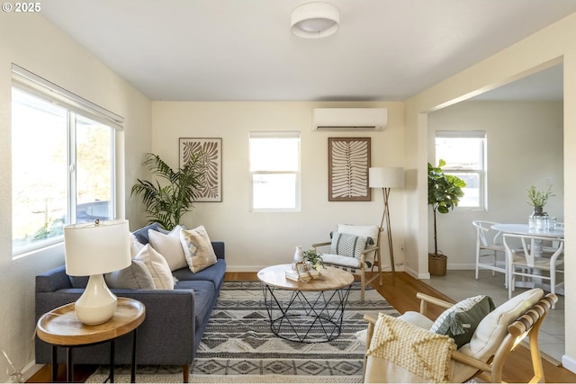 living area with a wall mounted air conditioner, wood finished floors, and baseboards