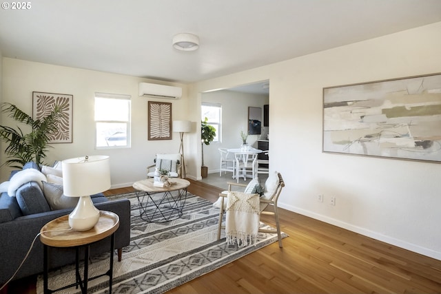 living room with a wall unit AC, baseboards, and wood finished floors