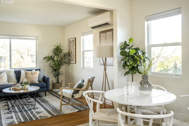 sitting room with plenty of natural light, an AC wall unit, and wood finished floors