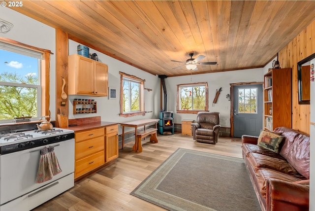 kitchen with white gas stove, open floor plan, wooden ceiling, ceiling fan, and a wood stove