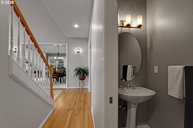 bathroom with wood finished floors, baseboards, recessed lighting, and a chandelier