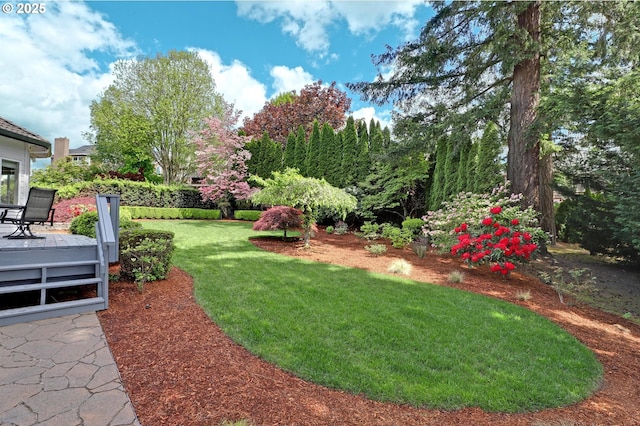 view of green lawn with a wooden deck