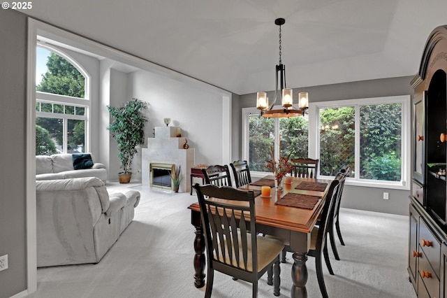 dining room with carpet floors, a chandelier, and a tile fireplace