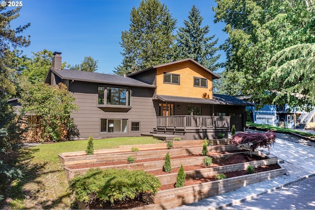 17349 Banyan Ln, Lake Oswego, OR 97034 - back of house featuring a chimney, a garden, covered porch, an attached garage, and a yard