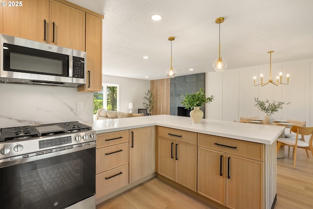 17349 Banyan Ln, Lake Oswego, OR 97034 - kitchen with stainless steel appliances, light brown cabinets, light wood-style flooring, light countertops, and a chandelier