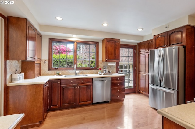 kitchen with appliances with stainless steel finishes, a sink, plenty of natural light, light countertops, and recessed lighting
