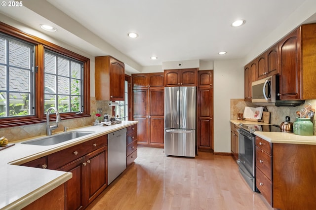 kitchen with stainless steel appliances, a sink, recessed lighting, light wood-style floors, and decorative backsplash