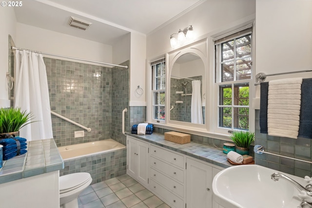 bathroom featuring tile patterned flooring, a sink, tiled shower / bath combo, and toilet