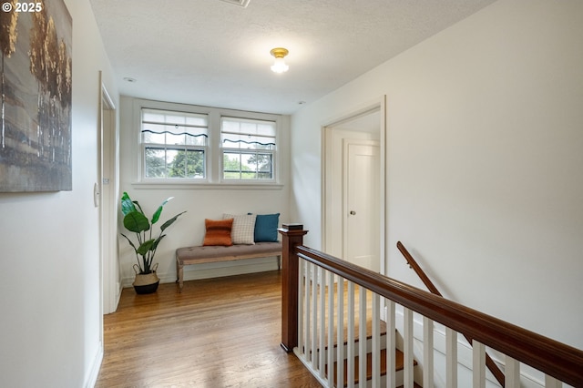 hall with an upstairs landing, wood finished floors, and baseboards